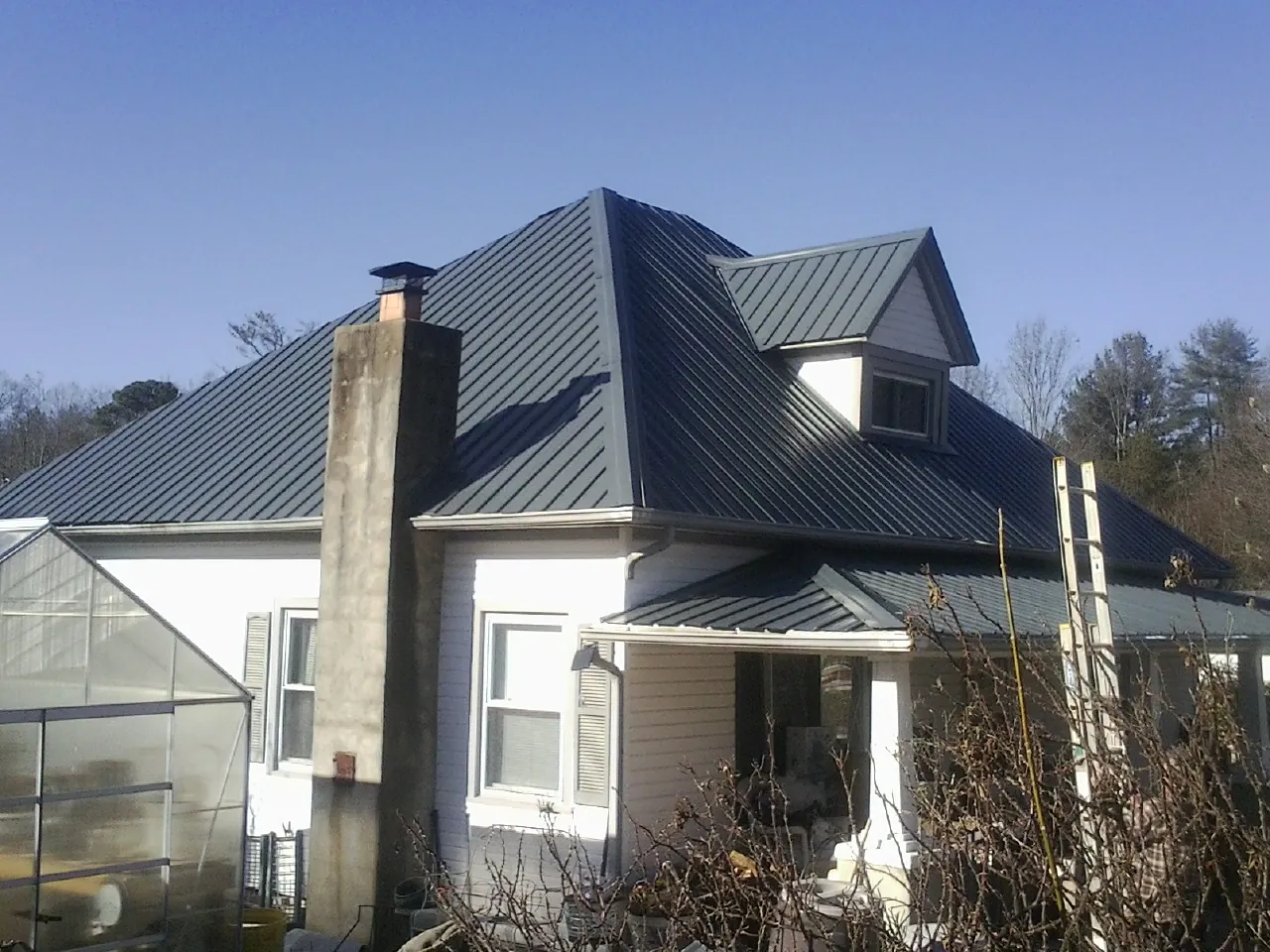 Dark blue standing seam metal roof on a white farmhouse with dormer — Slate & Tile Roof Repair by Roofing Brothers in Durham