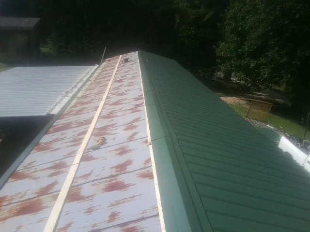 Old rusted panels beside newly installed green metal roofing — Wind Damage Roof Repair by Roofing Brothers in Durham