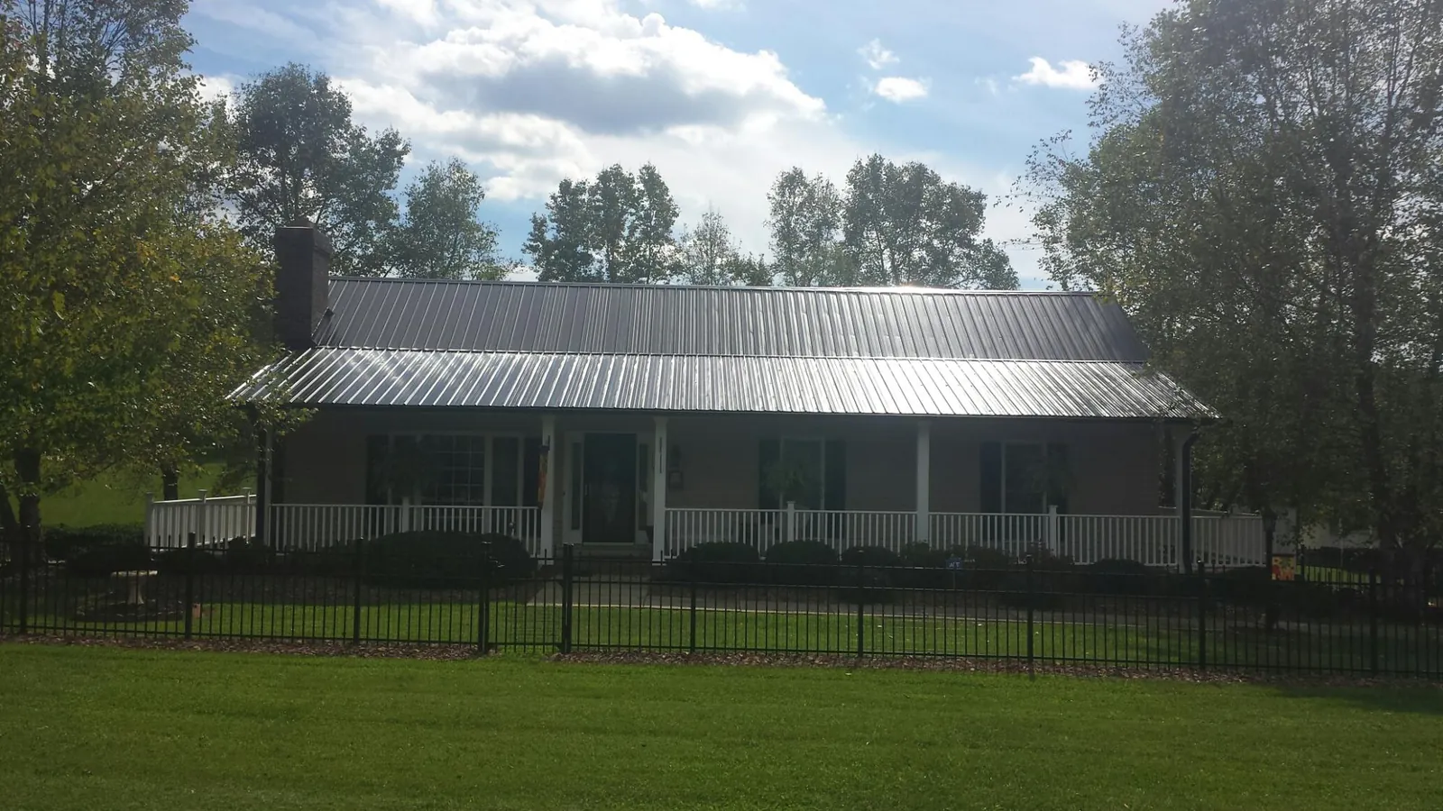 Gray metal roof on a brick ranch with a full width front porch — Gutter Guard Installation work by our crew in Durham
